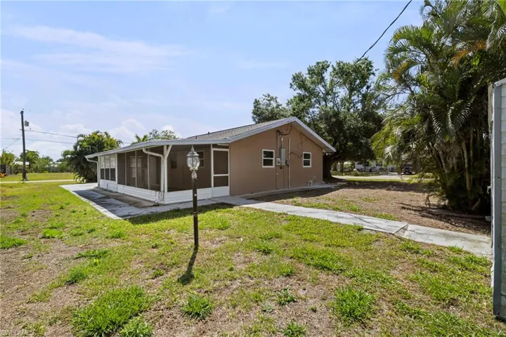 Rear view of property with a sunroom, stucco siding, and a lawn