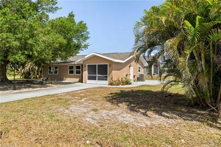Back of property featuring stucco siding, central air condition unit, and concrete driveway