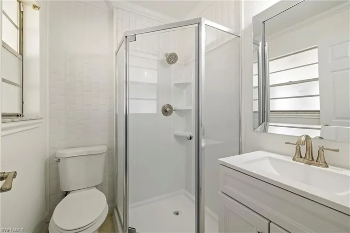 Full bath featuring toilet, vanity, crown molding, and a stall shower