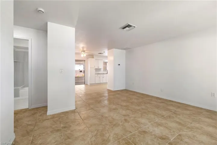 Empty room featuring light tile patterned floors, baseboards, ceiling fan, and visible vents