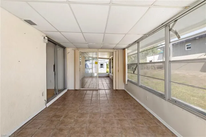 Unfurnished sunroom with baseboards, visible vents, tile patterned flooring, and a paneled ceiling