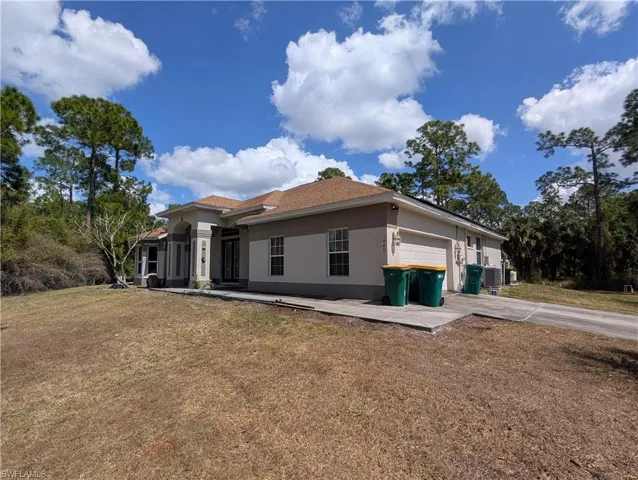 View of front of property with stucco siding, a garage, a front yard, and driveway
