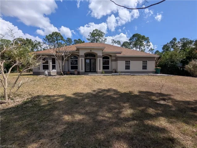 View of front of property featuring stucco siding, a front yard, and roof with shingles