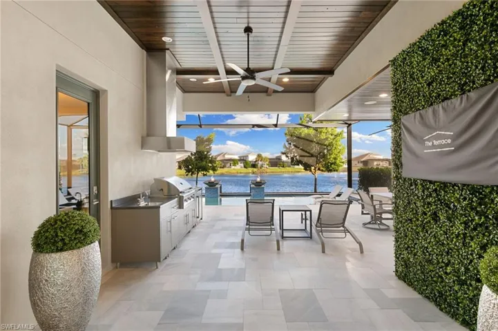 View of patio / terrace with exterior kitchen, a ceiling fan, a water view, and outdoor dining area