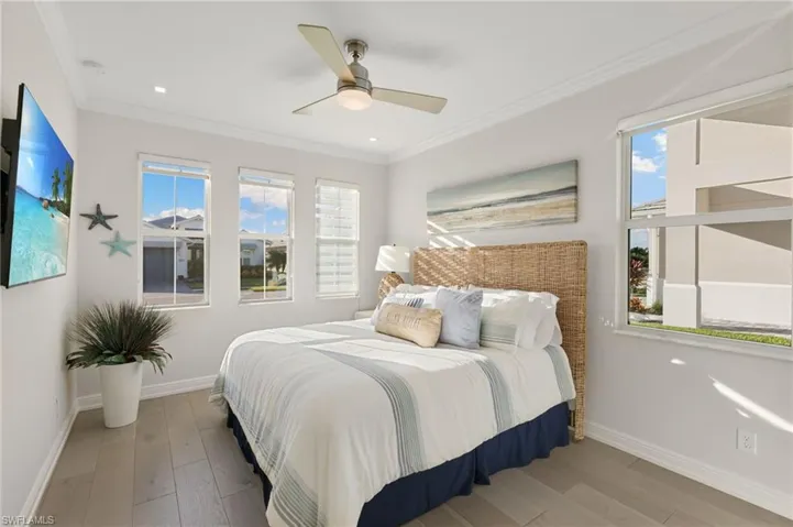Bedroom with hardwood / wood-style floors, ceiling fan, and ornamental molding