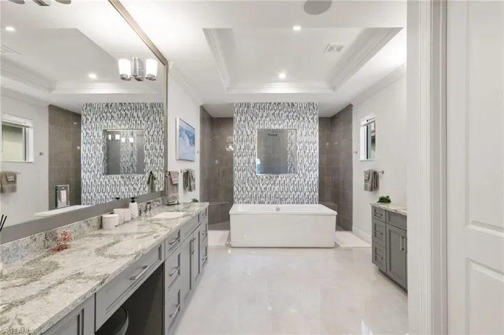 Full bathroom with crown molding, walk in shower, vanity, a tray ceiling, and a freestanding bath