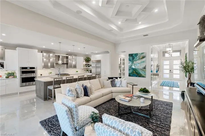 Living area featuring french doors, crown molding, a towering ceiling, recessed lighting, and a chandelier