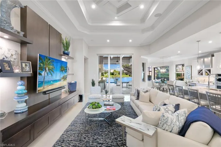 Living room with recessed lighting, a raised ceiling, a towering ceiling, and crown molding