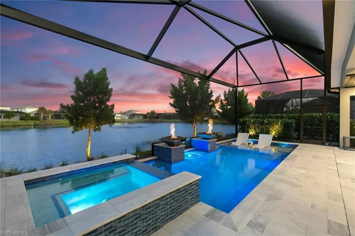 Outdoor pool with glass enclosure, an in-ground hot tub, a sunroom, and a water view