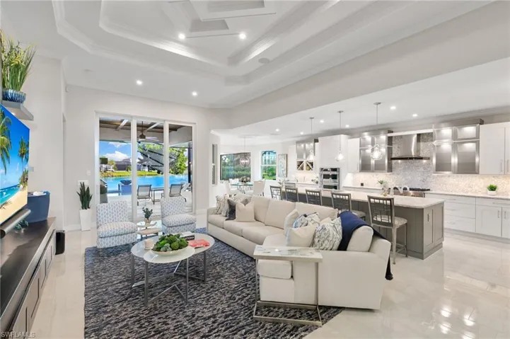 Living room with crown molding, recessed lighting, and a tray ceiling