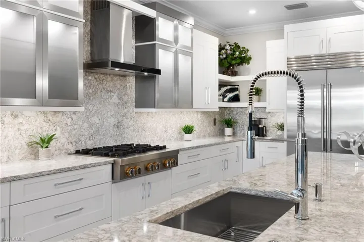 Kitchen with wall chimney range hood, open shelves, stainless steel appliances, white cabinets, and crown molding