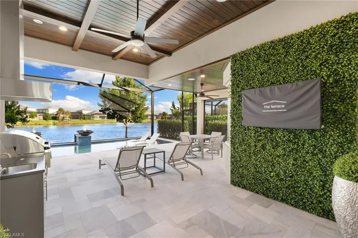 View of patio / terrace with a ceiling fan, outdoor dining area, a water view, exterior kitchen, and glass enclosure