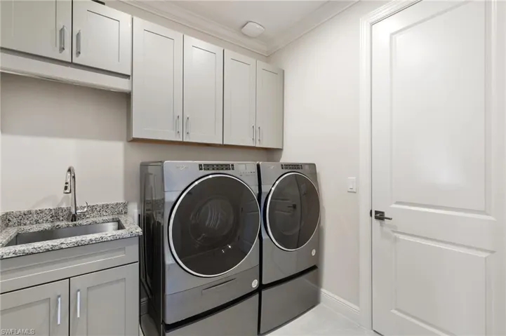 Laundry area featuring ornamental molding, independent washer and dryer, and cabinet space