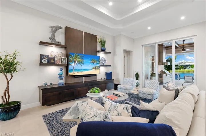 Living room with ornamental molding, a tray ceiling, ceiling fan, and recessed lighting