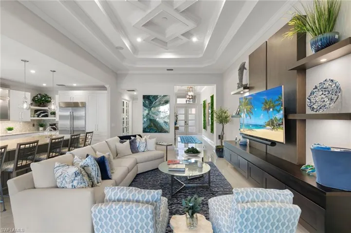 Living room with ornamental molding, recessed lighting, coffered ceiling, and a chandelier