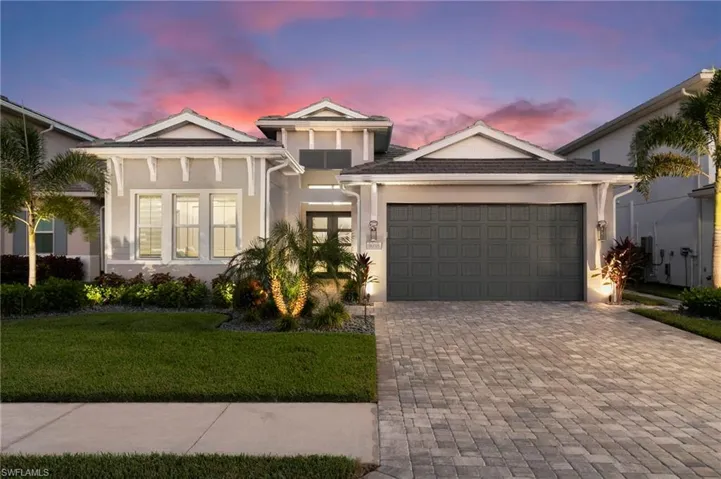 View of front of property featuring stucco siding, a lawn, decorative driveway, and an attached garage