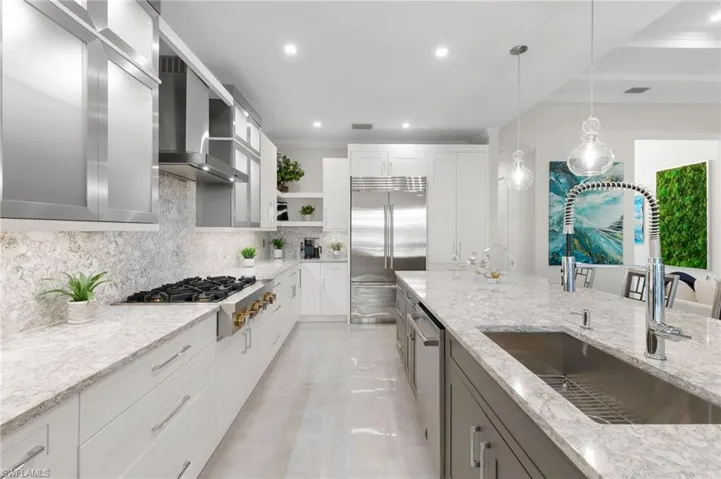 Kitchen featuring open shelves, hanging light fixtures, stainless steel appliances, light stone countertops, and recessed lighting