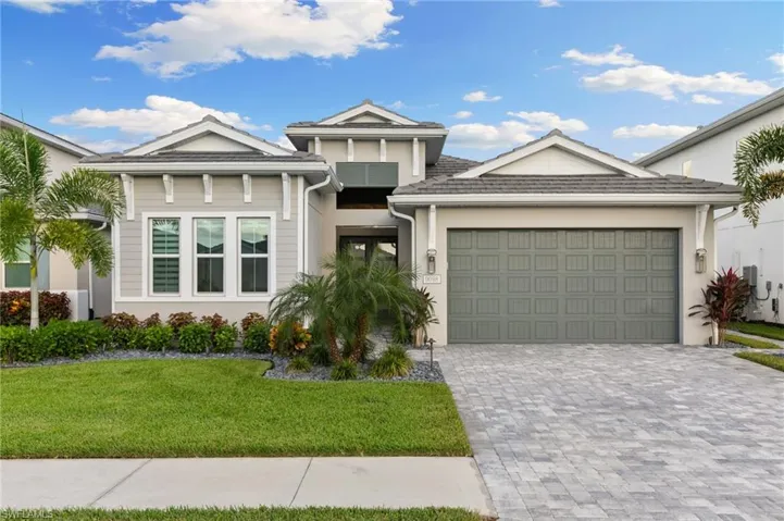 View of front facade featuring decorative driveway, a front lawn, an attached garage, and stucco siding