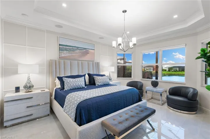 Bedroom featuring crown molding, a raised ceiling, a chandelier, and a water view