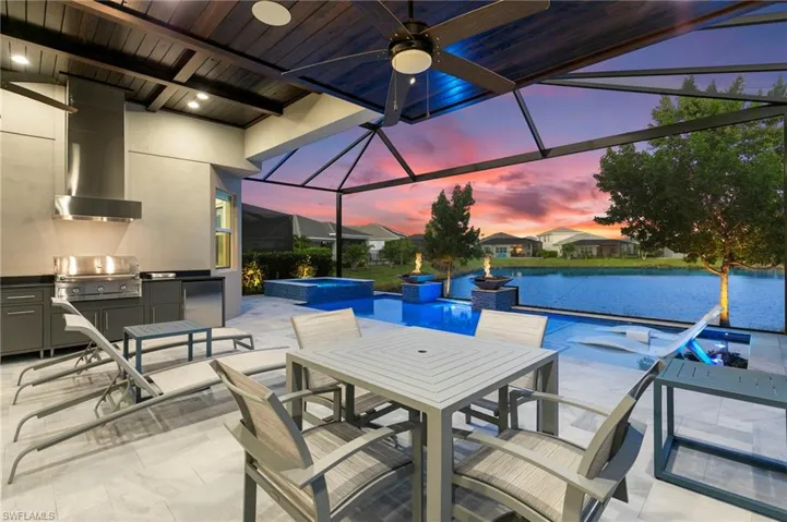 View of patio featuring a lanai, outdoor dining area, a sunroom, exterior kitchen, and a pool with connected hot tub