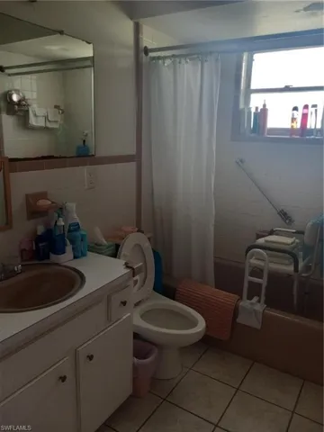Full bathroom featuring tile patterned floors, shower / bath combo with shower curtain, tile walls, and toilet