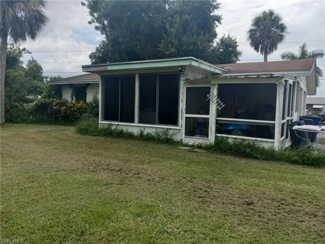 Rear view of property featuring a sunroom and a lawn