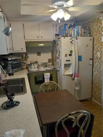 Kitchen with white cabinetry, ceiling fan, sink, tile patterned flooring, and refrigerator