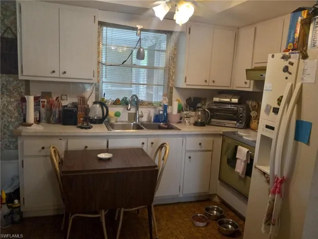 Kitchen with range with electric stovetop, sink, white refrigerator with ice dispenser, white cabinetry, and ceiling fan