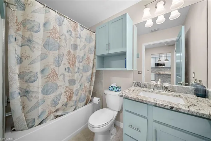 Bathroom featuring a light blue vanity with a granite-style countertop, an integrated sink, and a built-in medicine cabinet with open shelving