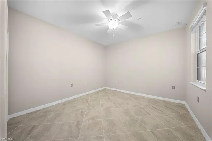 Tiled flooring, white trim, window, ceiling fan with integrated lighting, and neutral wall tones