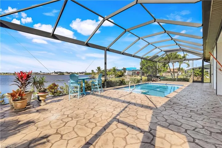 View of pool featuring glass enclosure, a patio area, and a water view