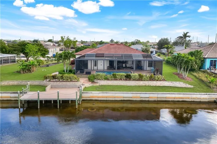 Back of house featuring a pool, a yard, a water view, and glass enclosure