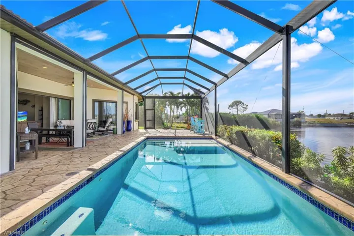 View of swimming pool featuring a lanai, an outdoor living space, ceiling fan, a water view, and a patio