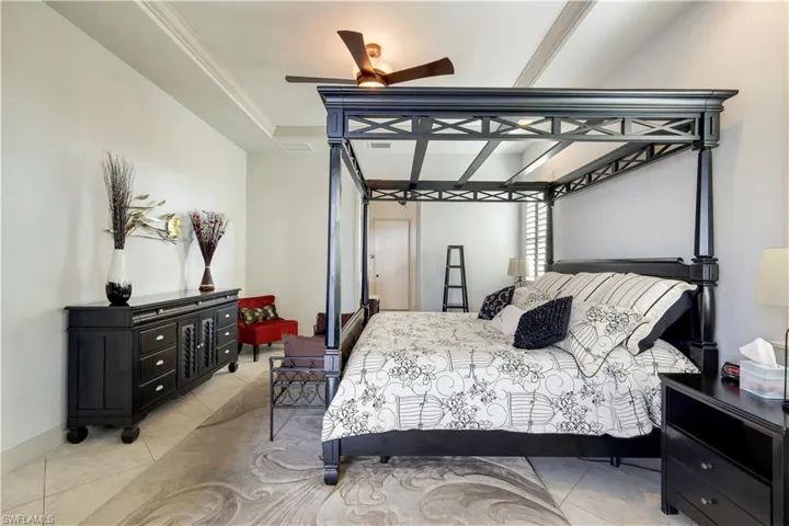 Bedroom with light tile patterned floors, ceiling fan, and crown molding