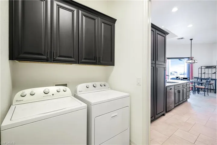 Laundry area featuring cabinets, light tile patterned floors, washing machine and dryer, and sink