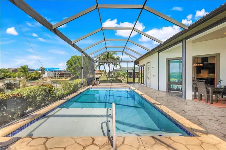 View of pool featuring glass enclosure and a patio area