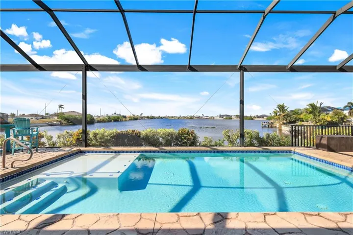 View of pool with glass enclosure, a patio area, and a water view