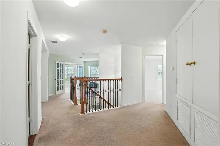 Hall featuring an upstairs landing and light carpet
