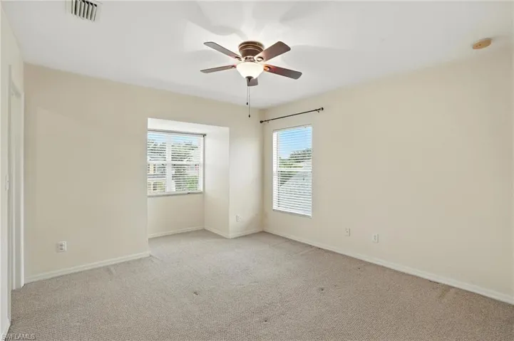 Unfurnished bedroom with light colored carpet, a ceiling fan, and a smoke detector