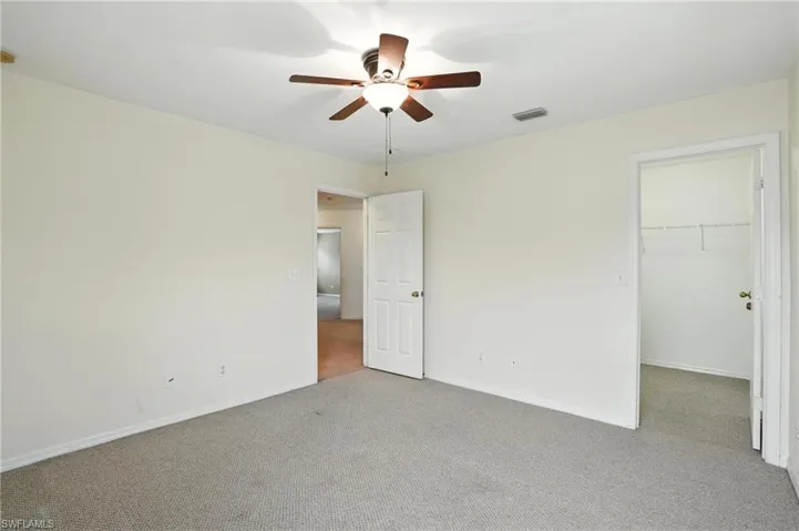 Unfurnished bedroom featuring carpet flooring, a spacious closet, a closet, and ceiling fan