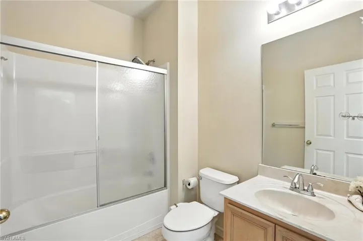 Bathroom featuring vanity and bath / shower combo with glass door