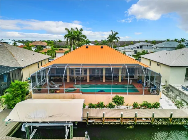 Back of property with a patio, boat lift, a lanai, an outdoor pool, and a residential view
