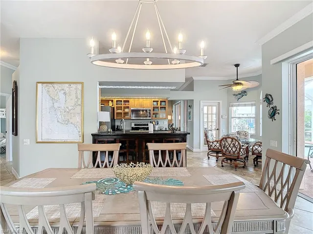 Dining area with ornamental molding, a ceiling fan, and a chandelier