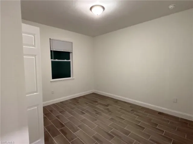 Empty room with baseboards and wood finish floors