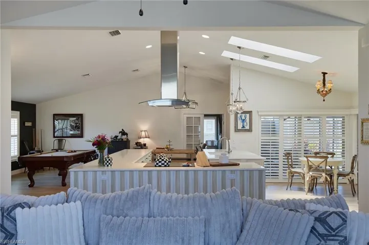Living room featuring a chandelier, light wood-style flooring, a skylight