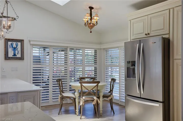 Dining area with an inviting chandelier, light wood-style flooring, and vaulted ceiling with skylight