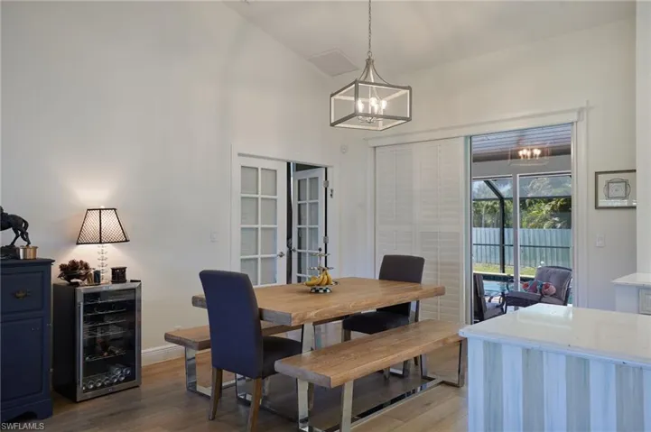 Dining room a notable chandelier, baseboards, high vaulted ceiling, and light wood-type flooring