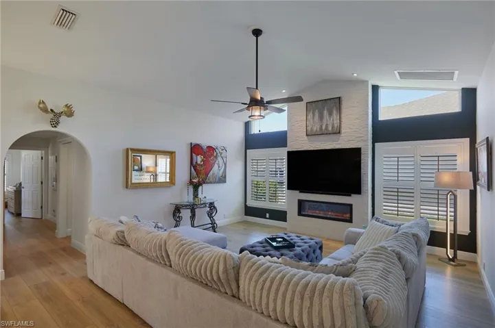Living area with lofted ceiling, baseboards,  ceiling fan, and arched walkways