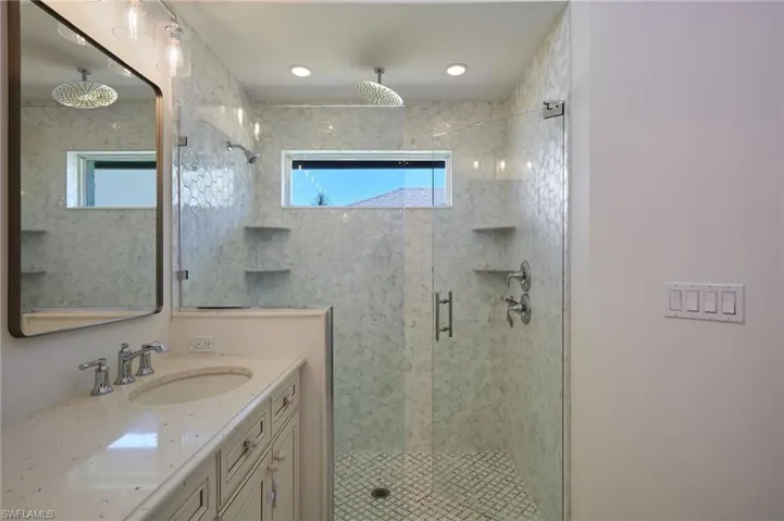 Bathroom with a shower stall, a wealth of natural light, and vanity