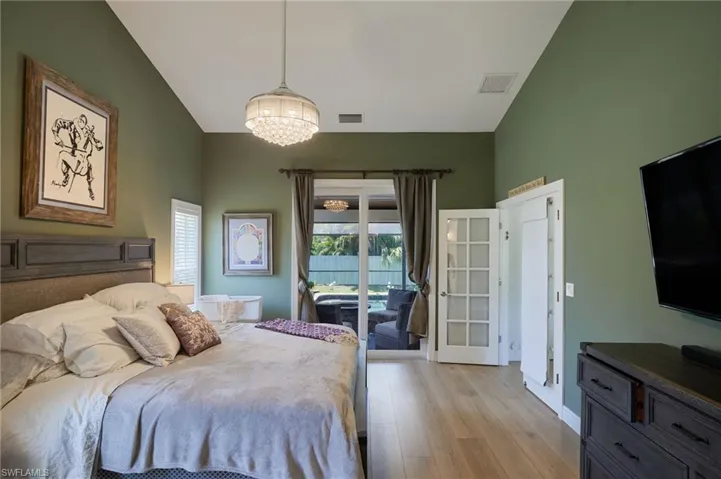 Bedroom featuring an inviting chandelier, access to outside, light wood-type flooring